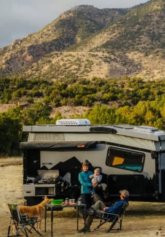 Familie entspannt sich neben ihrem Camper in den Bergen