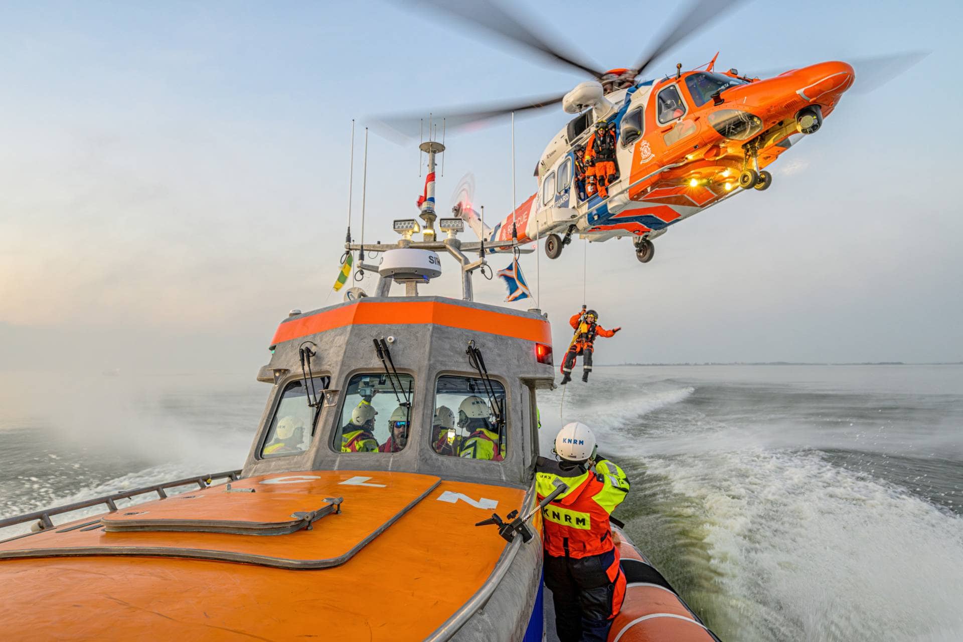 KNRM-Rettungsboot auf See mit einem Rettungshubschrauber, der ein Besatzungsmitglied an Bord holt